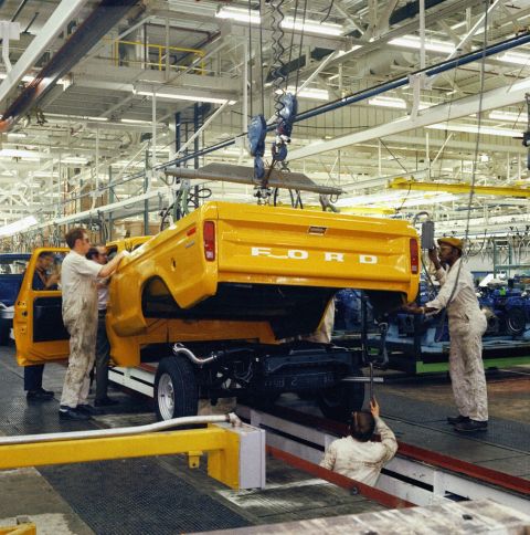 1994 Ford Bronco - Workers assemble a yellow Ford truck body on a factory production line.