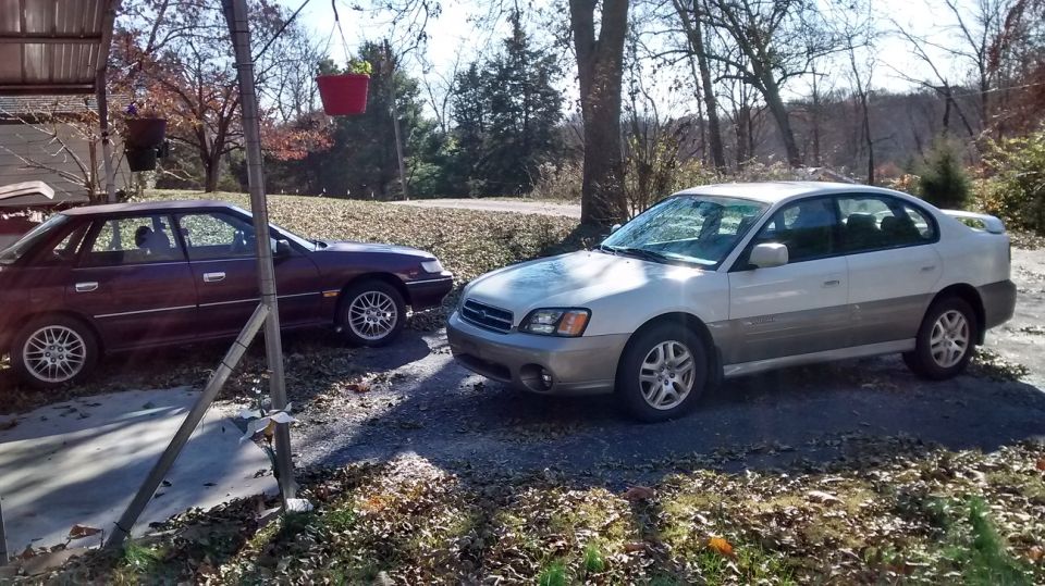 two Subaru sedans parked outside, one silver and gray, the other dark red