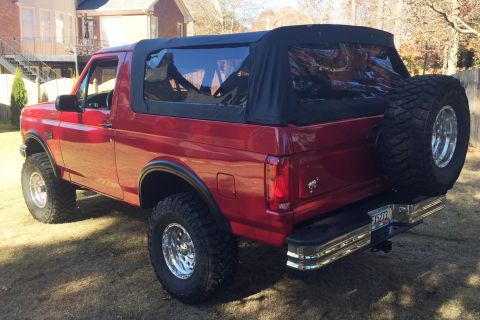 1994 Ford Bronco - Red 1994 Ford Bronco with a soft top and spare tire mounted on the rear.