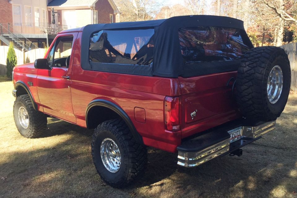 1994 Ford Bronco rear view, red paint, black soft top, spare tire on back