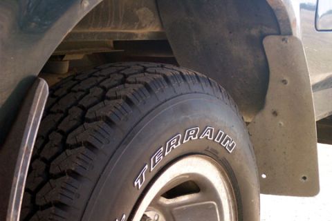 1995 Ford Bronco - A close-up shot focuses on the tire and mud flap of a vehicle, showing off-road tire tread.