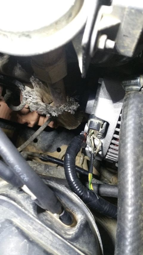 1996 Ford Bronco - Close-up view of the alternator and its wiring harness, showing some wear on the insulation.