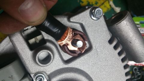 1996 Ford Bronco - Connecting a wire terminal to the alternator post, likely for an upgrade or repair.
