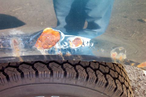 1995 Ford Bronco - Close-up of a vehicle's lower body panel showing extensive rust damage.