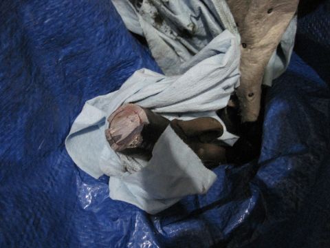 1994 Cadillac Fleetwood - A metal component, possibly a steering box, is covered by cloth on a blue tarp.