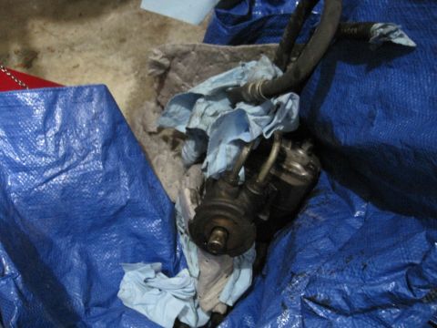 1994 Cadillac Fleetwood - Power steering pump assembly with hoses, partially covered by rags and a blue tarp.