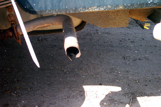Damaged exhaust pipe on a vehicle. The pipe is bent and the end is jagged