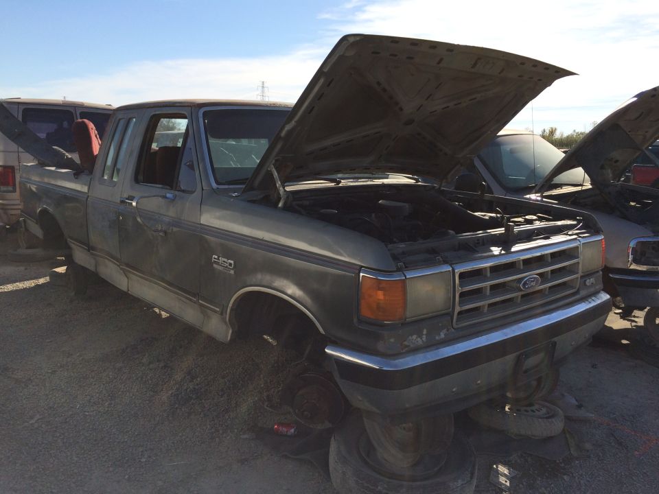 Gray Ford F-150 pickup truck with hood open, missing wheels