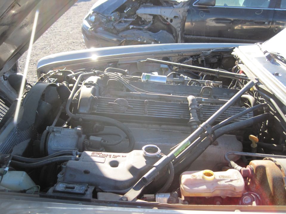 1985 Jaguar XJ6 engine bay with hood open, showing V12 engine, radiator, and coolant reservoir