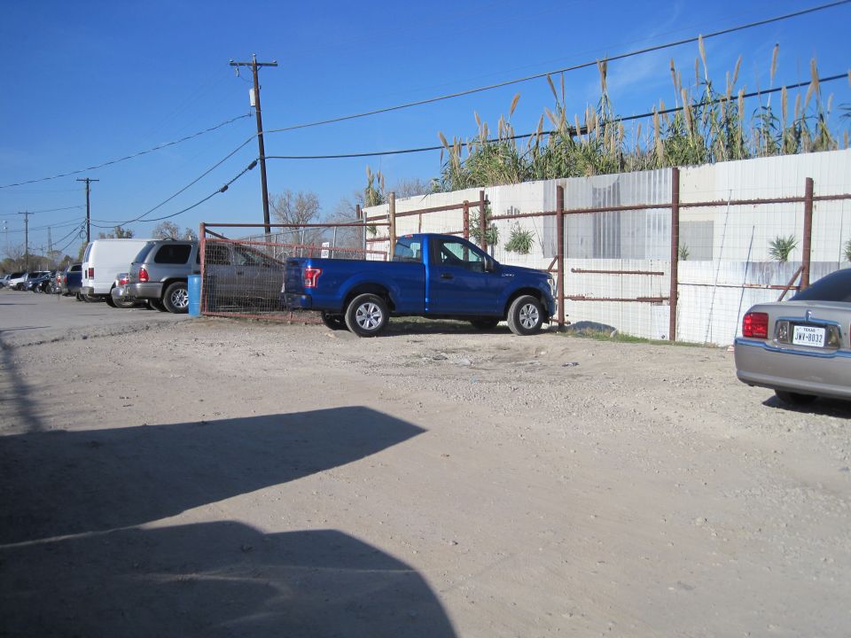 Blue pickup truck parked next to a fence