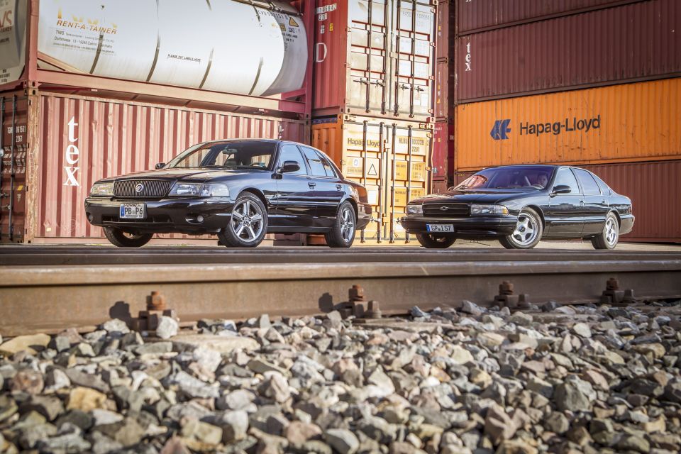 Black Mercury Marauder and a black Chevrolet Impala parked side-by-side on train tracks