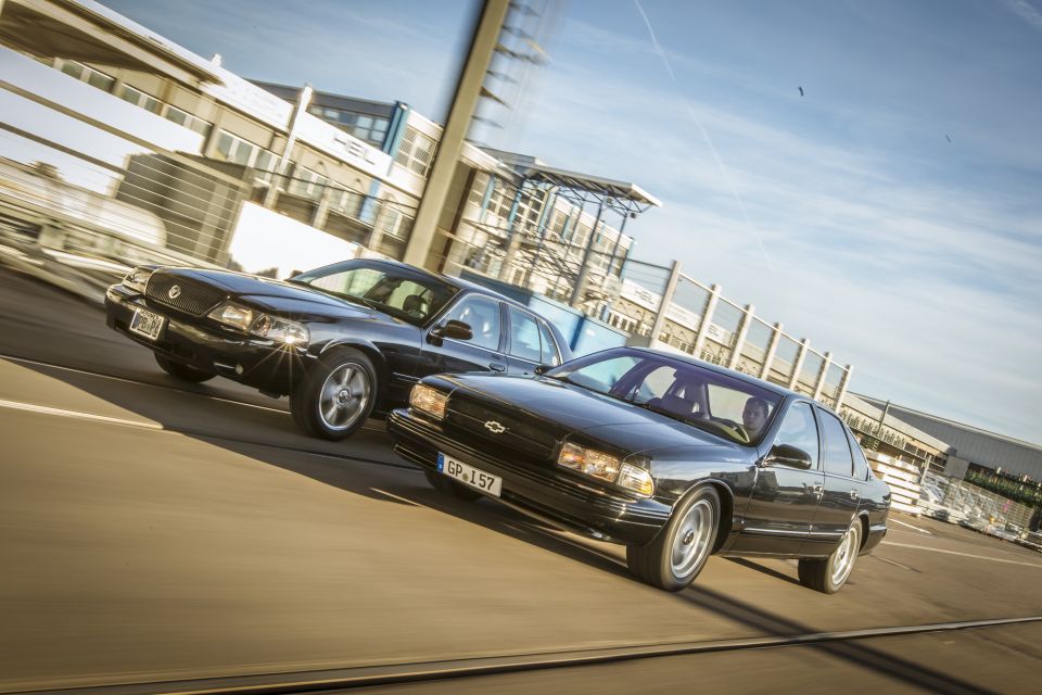 Black 2003 Mercury Marauder and another black sedan driving on a road