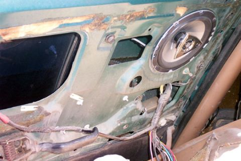 1995 Ford Bronco - Interior view of a stripped teal-green door shell with the trim panel removed, showing a newly mounted aftermarket coaxial speaker in the l…