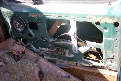 1995 Ford Bronco - Interior of a teal-green door shell with the trim panel removed, exposing the window regulator, door latch rods, wiring and a coaxial speak…