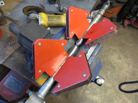 1967 Ford F-250 - Magnetic welding clamps hold a metal rod in place for fabrication work, with tools visible in the background.