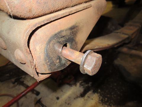 1967 Ford F-250 - Close-up of a rusty bolt securing a bracket, with a leaf spring in the background.