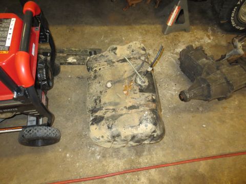 1967 Ford F-250 - A fuel tank and transmission are shown on a garage floor, with a generator nearby.