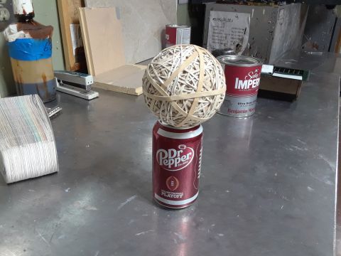 1994 Ford Bronco - A large ball made of rubber bands sits atop a Dr. Pepper can on a metal workbench.