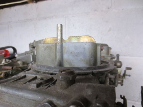 1967 Ford F-250 - A carburetor part with visible markings is shown against a white brick wall.