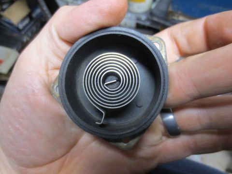 1967 Ford F-250 - A close-up view of a coiled spring mechanism within a black casing, held in a person's hand.