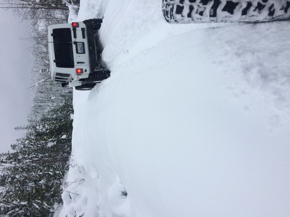 White Jeep Wrangler with snow piled high on its side
