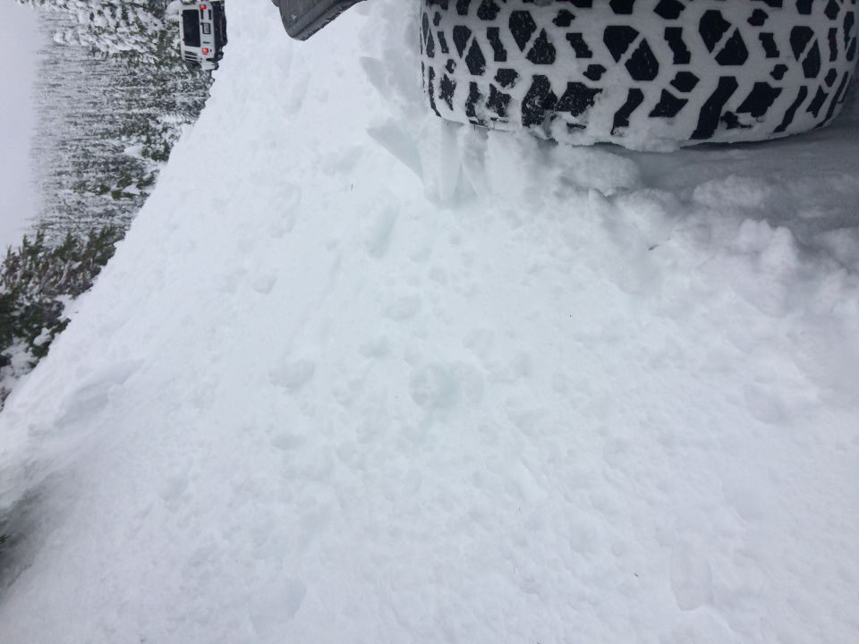 Jeep Wrangler in snow, tire visible. Another vehicle in background