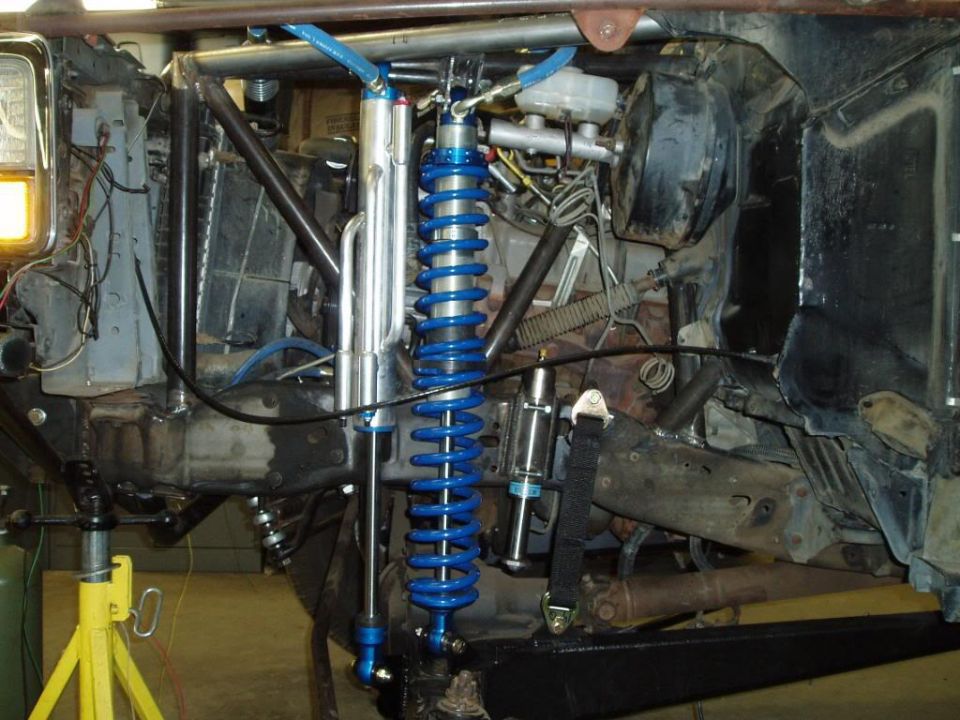 Custom off-road suspension with blue coilover shocks and suspension linkages