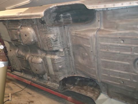 1964 Ford Galaxie - The undercarriage of a 1964 Ford Galaxie is visible, with the floor pan and frame rails exposed.