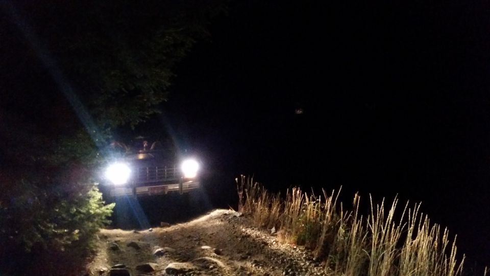 off-road vehicle with headlights on driving on a dirt path at night