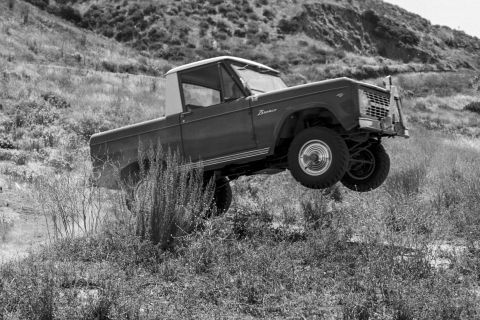 1974 Ford Bronco - This Ford Bronco is captured mid-air while driving off-road, its suspension and off-road capabilities.