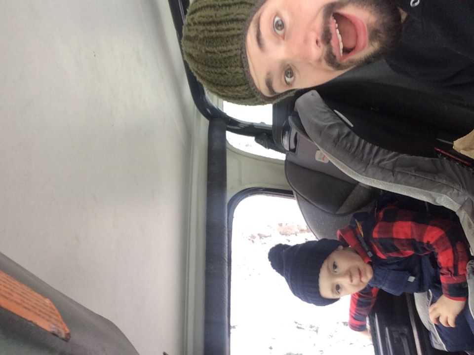 Man and child in car interior, child in car seat. Snow visible outside
