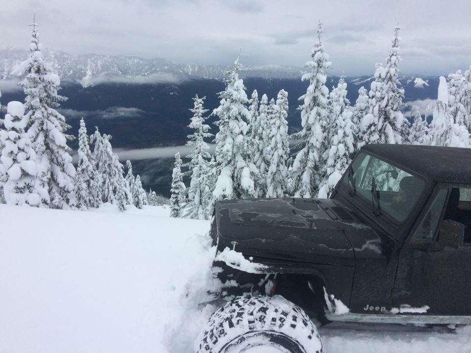 Black Jeep in snow, front fender and tire visible, with Supermotors logo on lower door