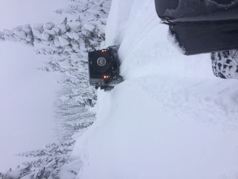1995 Jeep Wrangler - A Jeep Wrangler navigates a snow-covered mountain path, with a second vehicle's rear visible.