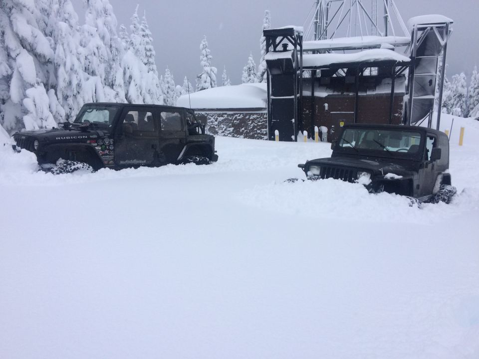 Two black Jeeps partially buried in snow, one a four-door model with 'Rubicon' visible