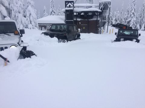 1995 Jeep Wrangler - Multiple Jeeps are stuck in deep snow near a building during a winter storm.