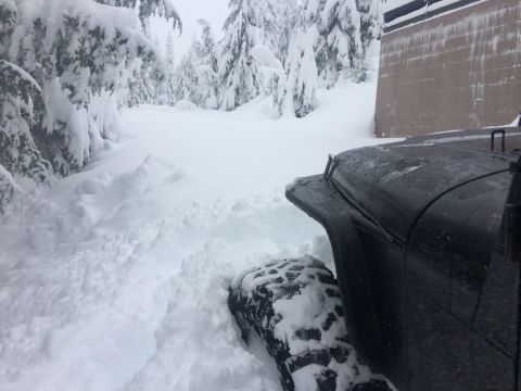 1995 Jeep Wrangler - A black 1995 Jeep YJ navigates through a snow-covered trail, with its front fender and tire partially submerged in the deep snow.