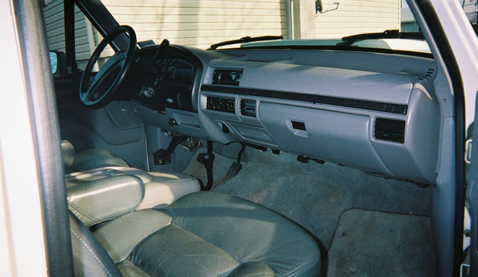 Gray truck interior with dashboard, radio, shifter and leather seats seen from passenger door