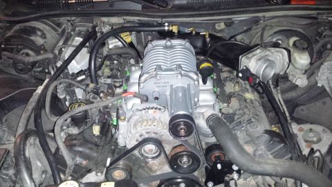 2005 Mercury Grand Marquis - Engine bay with a silver supercharger installed. Text on supercharger reads 'BOOST GATE VQ140'.