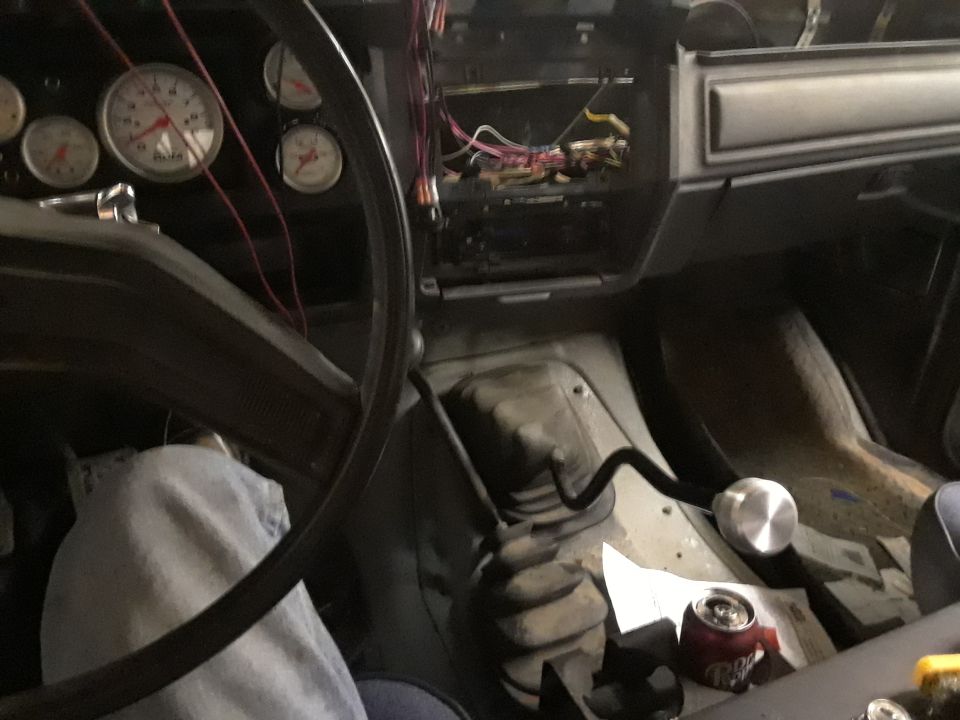 Interior view of a vehicle with steering wheel, gauges, and gear shifter.