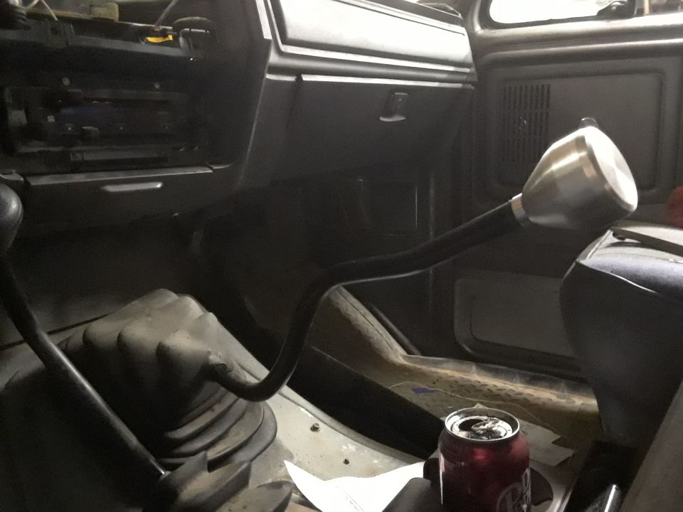 Interior view of a vehicle's center console with two shifters and a soda can.