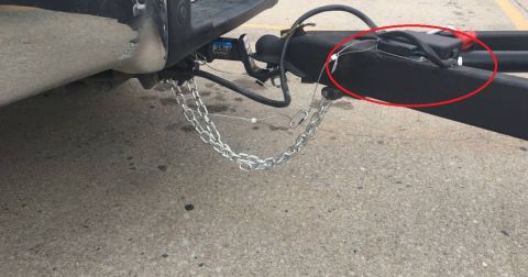 1995 Mercury Grand Marquis - A close-up view shows the trailer hitch assembly of a vehicle, including safety chains and a black electronic box attached to the trailer f…