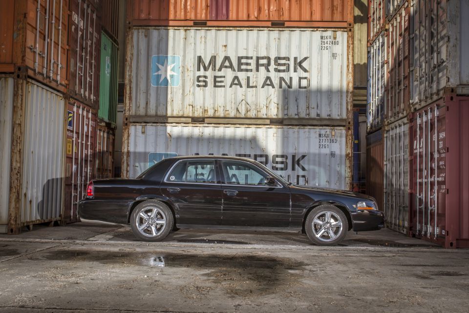 Black 2003 Mercury Marauder parked between shipping containers.