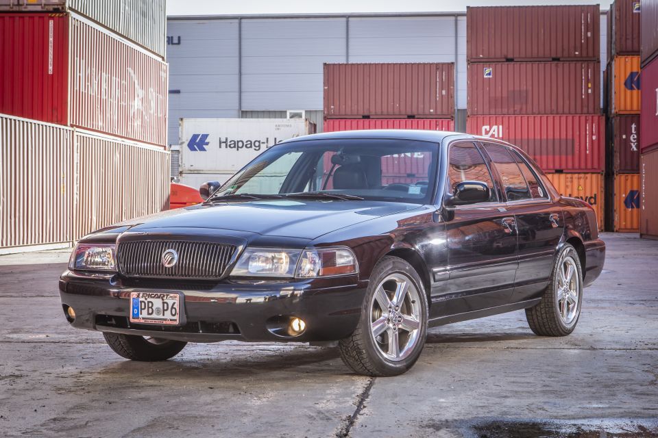 Black 2003 Mercury Marauder parked in front of shipping containers, front 3/4 view.
