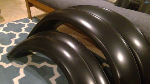 1994 Ford Bronco - Three black fender flares are stacked on top of each other. The flares are curved and appear to be made of plastic.