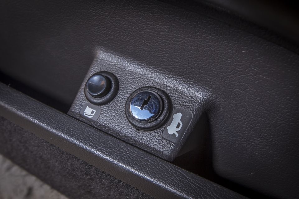 Close-up of fuel door and hood release buttons inside a car.