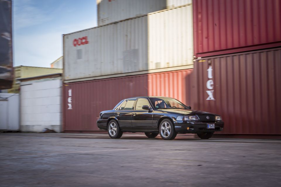 Black 2003 Mercury Marauder parked in front of stacked shipping containers.