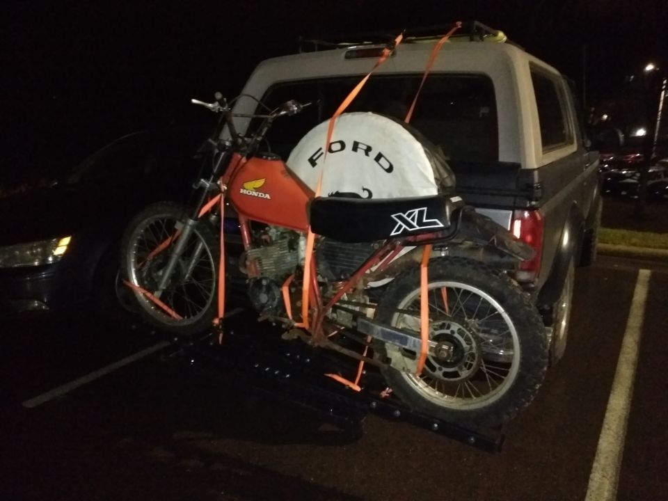 Orange Honda dirt bike loaded onto a carrier on the back of an SUV.