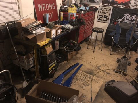 1995 Ford F-150 - A cluttered garage scene with various automotive parts and tools. A red toolbox, a workbench with boxes, a speed limit sign, and a car jack…