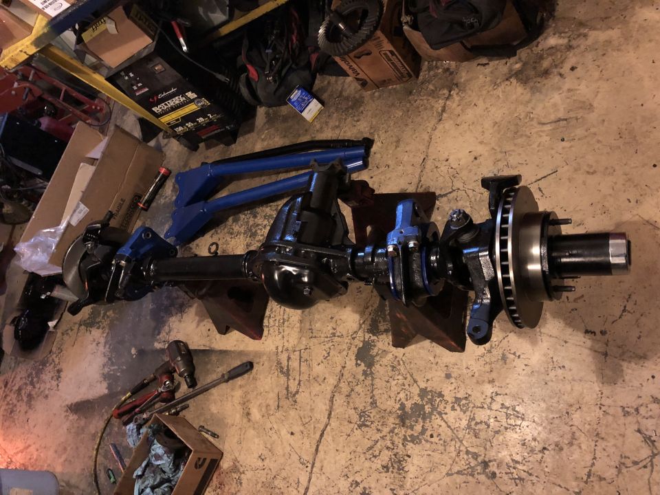 Black front axle assembly with disc brakes and suspension components.
