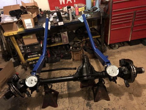 1995 Ford F-150 - A black rear axle assembly with disc brakes and a dial indicator is mounted on red jack stands. Blue support arms are attached to the axle,…